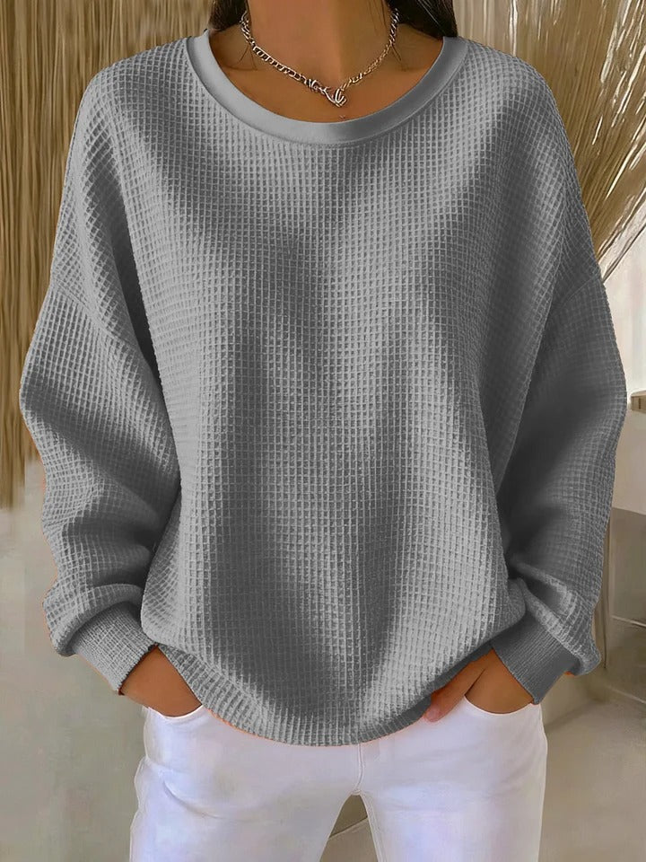 Pull gaufré gris à col rond et épaules tombantes, porté avec un pantalon blanc et un collier argenté. 3