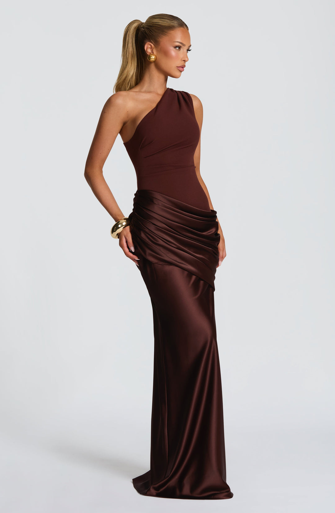 Robe marron vue de trois quarts, mannequin de profil, jupe satinée longue et drapé plissé sur le côté. 8