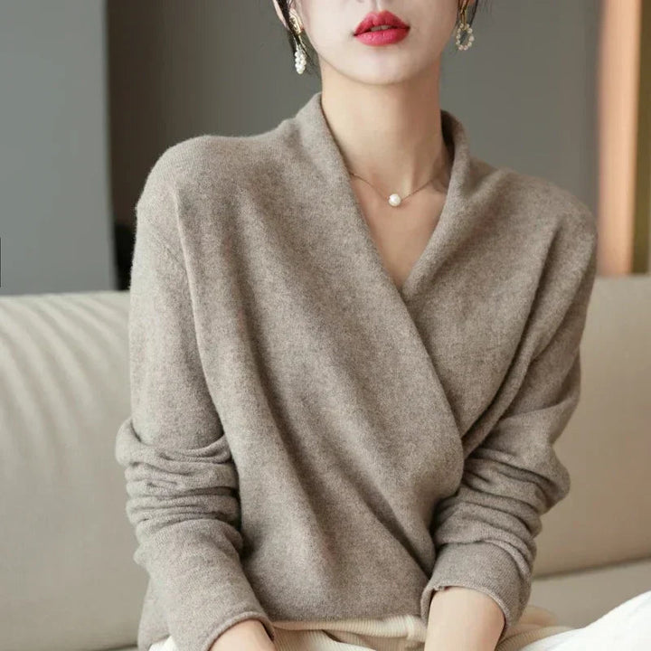 Pull croisé beige taupe porté face caméra, assise sur un canapé, boucles d'oreilles en perles 9