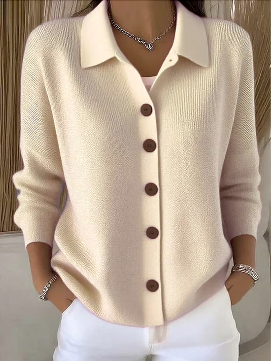 Femme portant le cardigan beige clair, boutons marron sur le devant, mains dans les poches d'un pantalon blanc, vue de face. 1