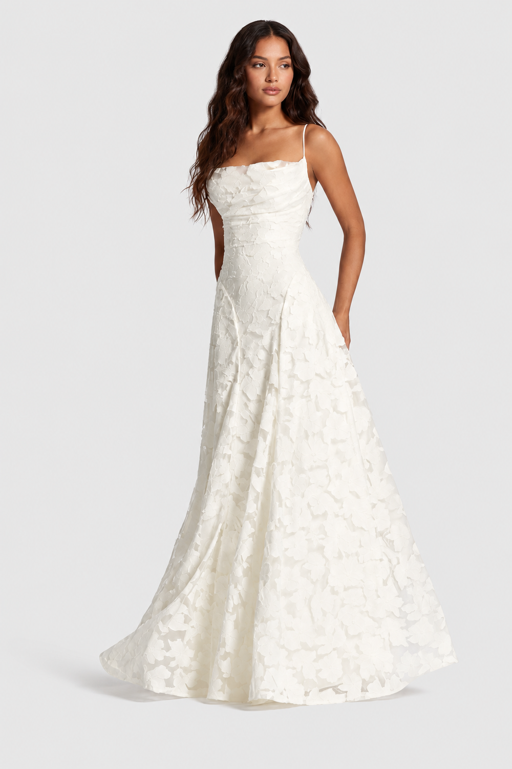 Robe blanche en dentelle florale en relief, encolure drapée et jupe évasée, portée par une mannequin de face, main dans la poche. 2