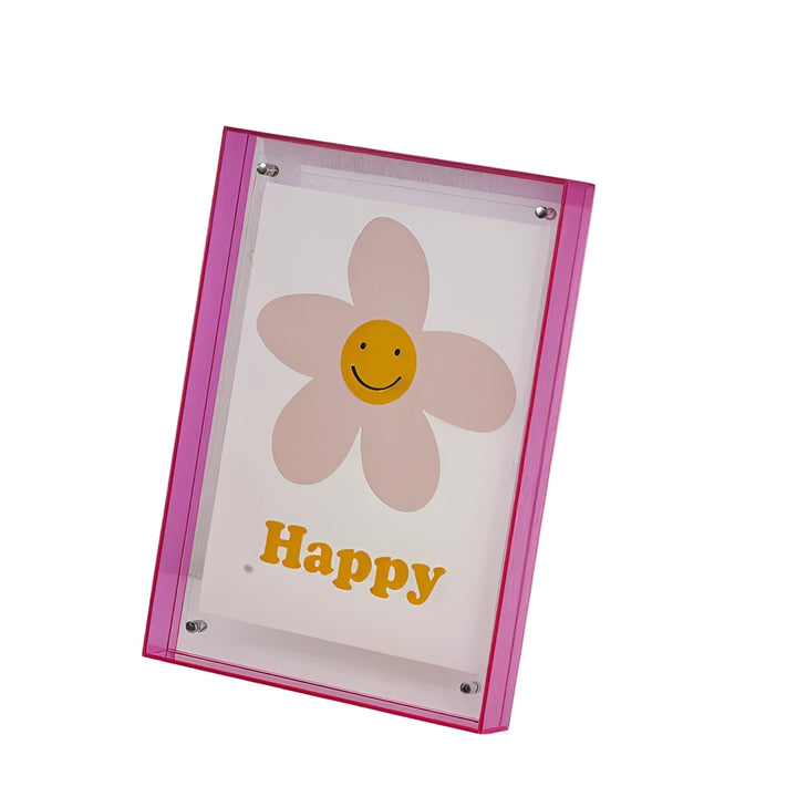 Cadre acrylique à bords rose néon, vu de face, présentant une illustration de fleur rose à cœur souriant jaune. 1