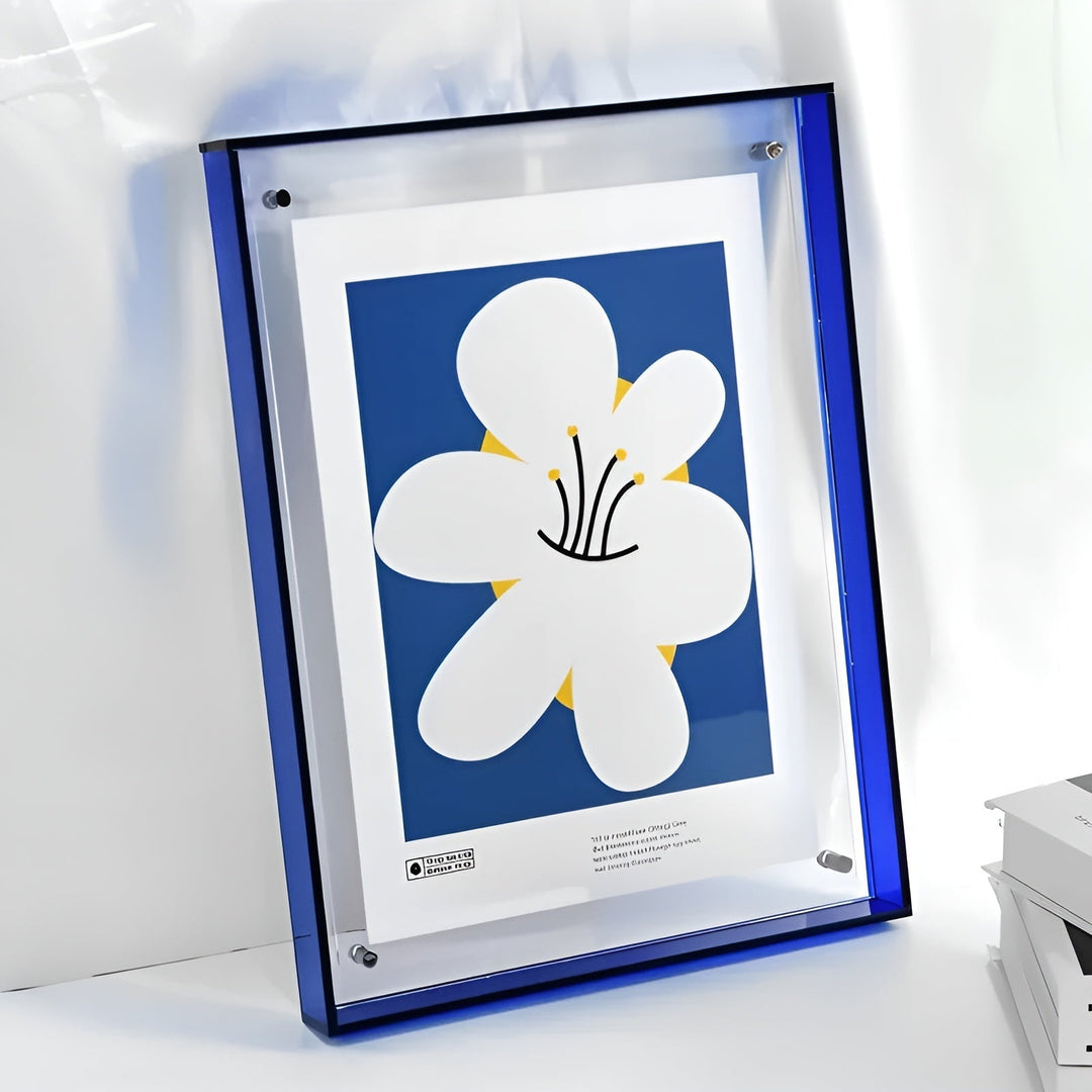 Cadre acrylique à bords bleu foncé appuyé contre un mur, avec une affiche d'une grande fleur blanche sur fond bleu. 14