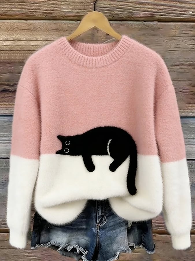 Version rose et blanche du pull duveteux au chat noir couché, suspendue sur un cintre devant des planches de bois. 3