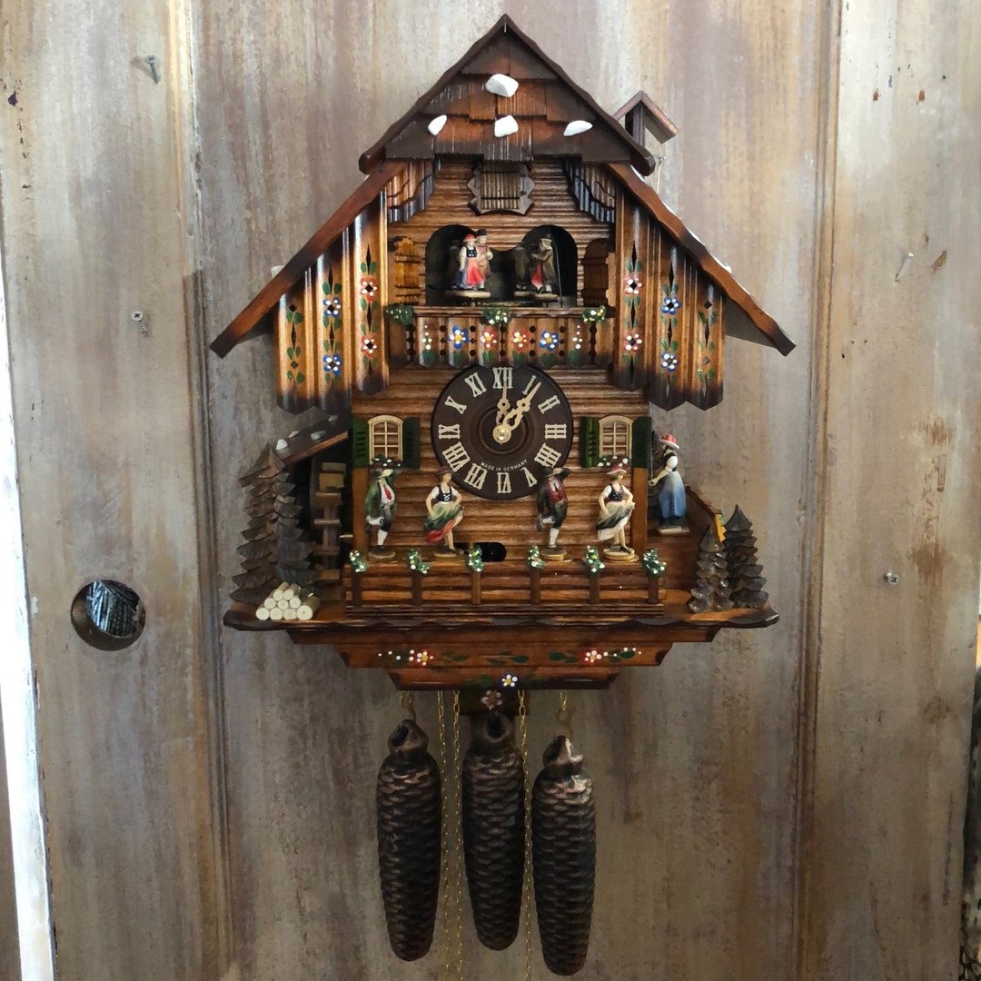 Pendule chalet accrochée à un mur de bois patiné, avec poids en pigne, danseurs sur la terrasse et roue à aubes. 12