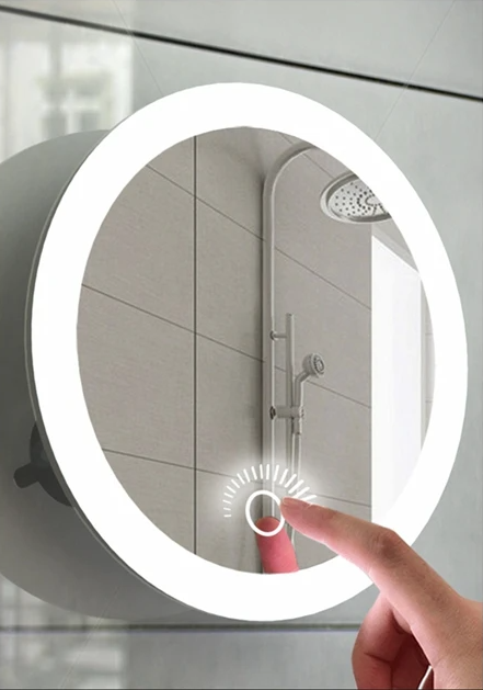 Miroir rond fixé sur une paroi de douche, un doigt touchant la commande tactile de l'anneau lumineux 1
