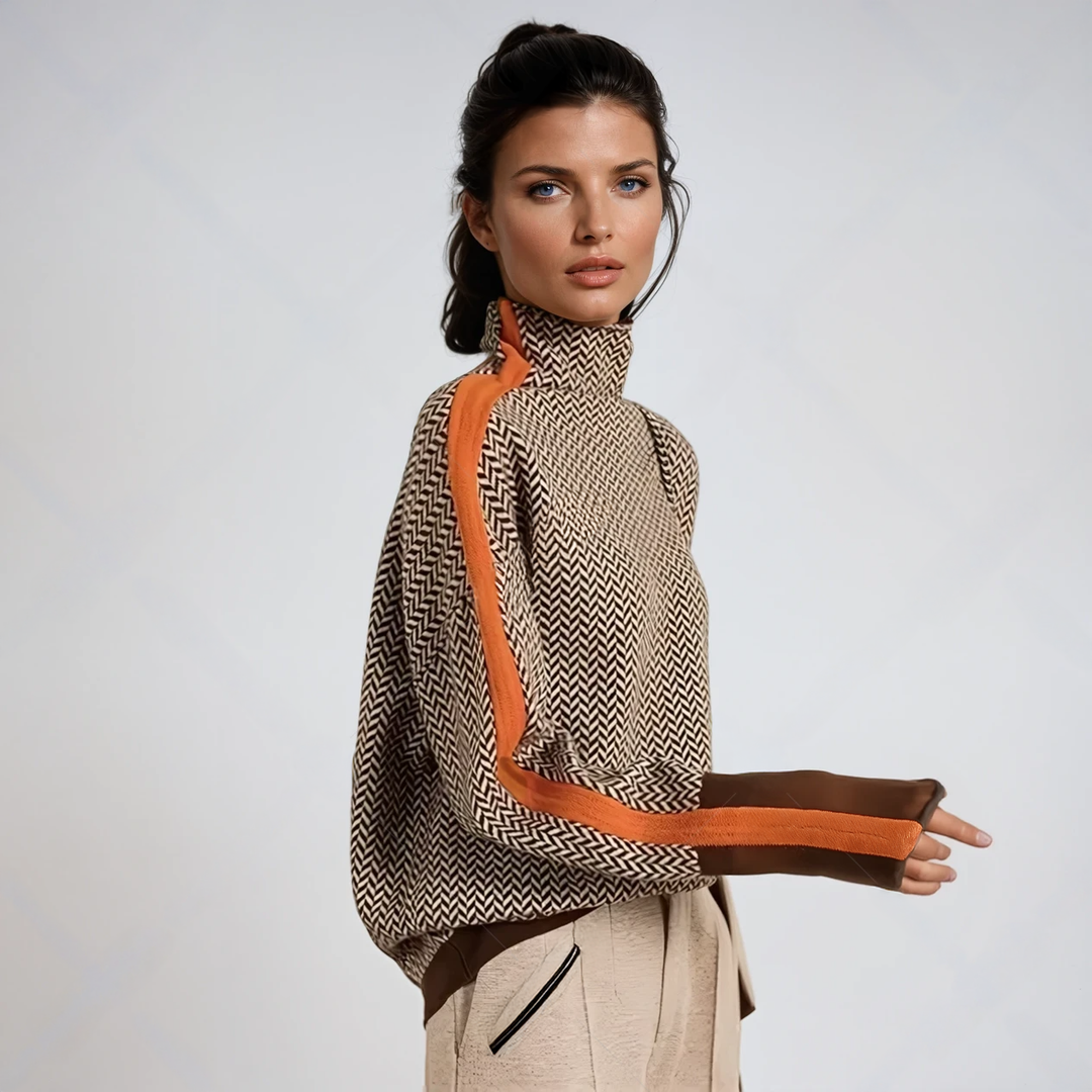 Mannequin de profil portant le pull à chevrons marron et beige, bande orange sur la manche, poignets avec passe-pouce, pantalon crème. 1