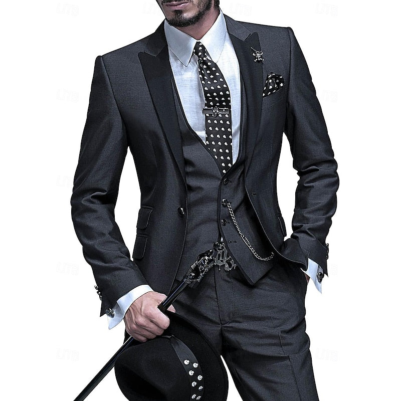 Homme portant le costume trois pièces gris anthracite à revers noirs, cravate à pois, chaîne de gilet, canne et chapeau noir à la main. 1
