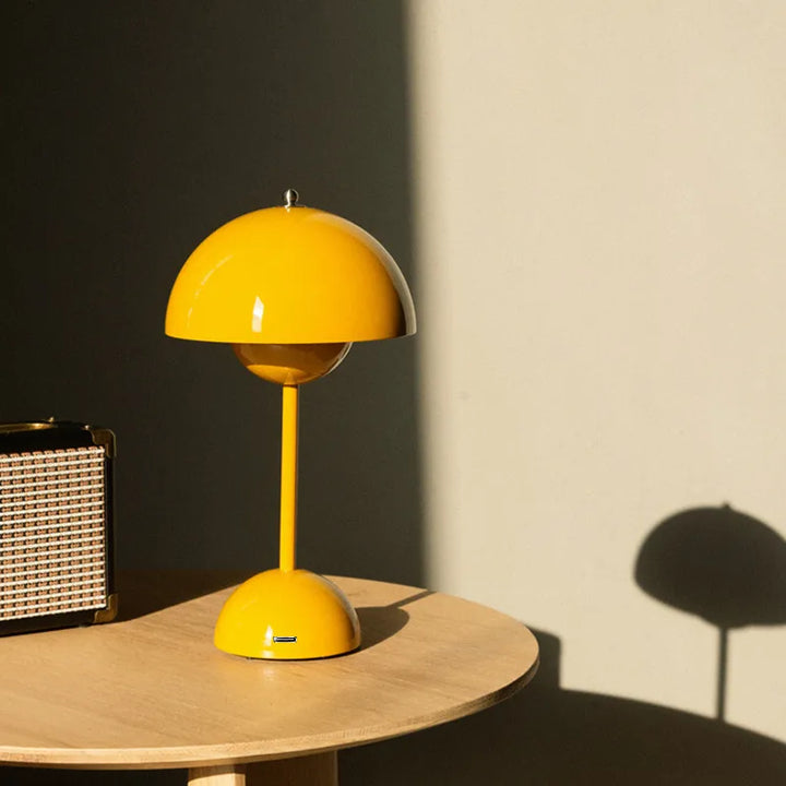 Lampe champignon jaune posée sur une table ronde en bois, avec une ombre portée sur le mur et une radio vintage. 4