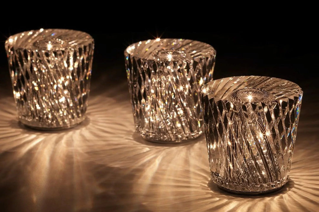 Trois lampes en cristal à motif en losanges allumées en perspective, avec des reflets lumineux rayonnants sur la surface. 14