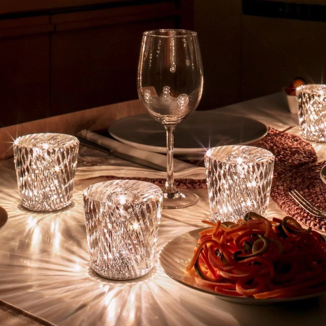 Quatre lampes en cristal à motif en losanges scintillantes sur une table dressée avec verre à vin et assiette de légumes. 5
