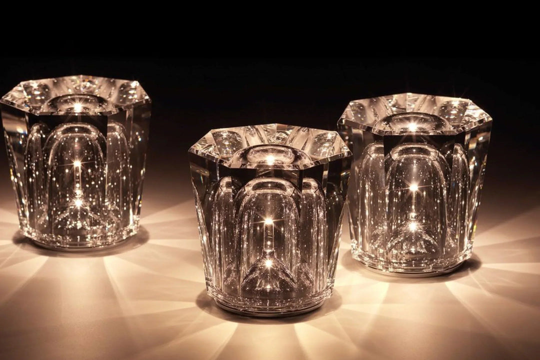 Trois lampes en cristal octogonales allumées, aux cloches intérieures lumineuses, projetant des rayons de lumière chaude sur le plan. 15