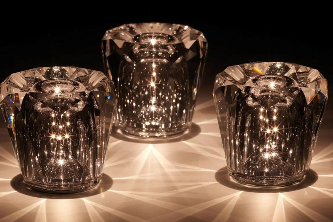 Trois lampes en cristal taillé en facettes allumées dans le noir, projetant des rayons de lumière chaude sur la table. 1
