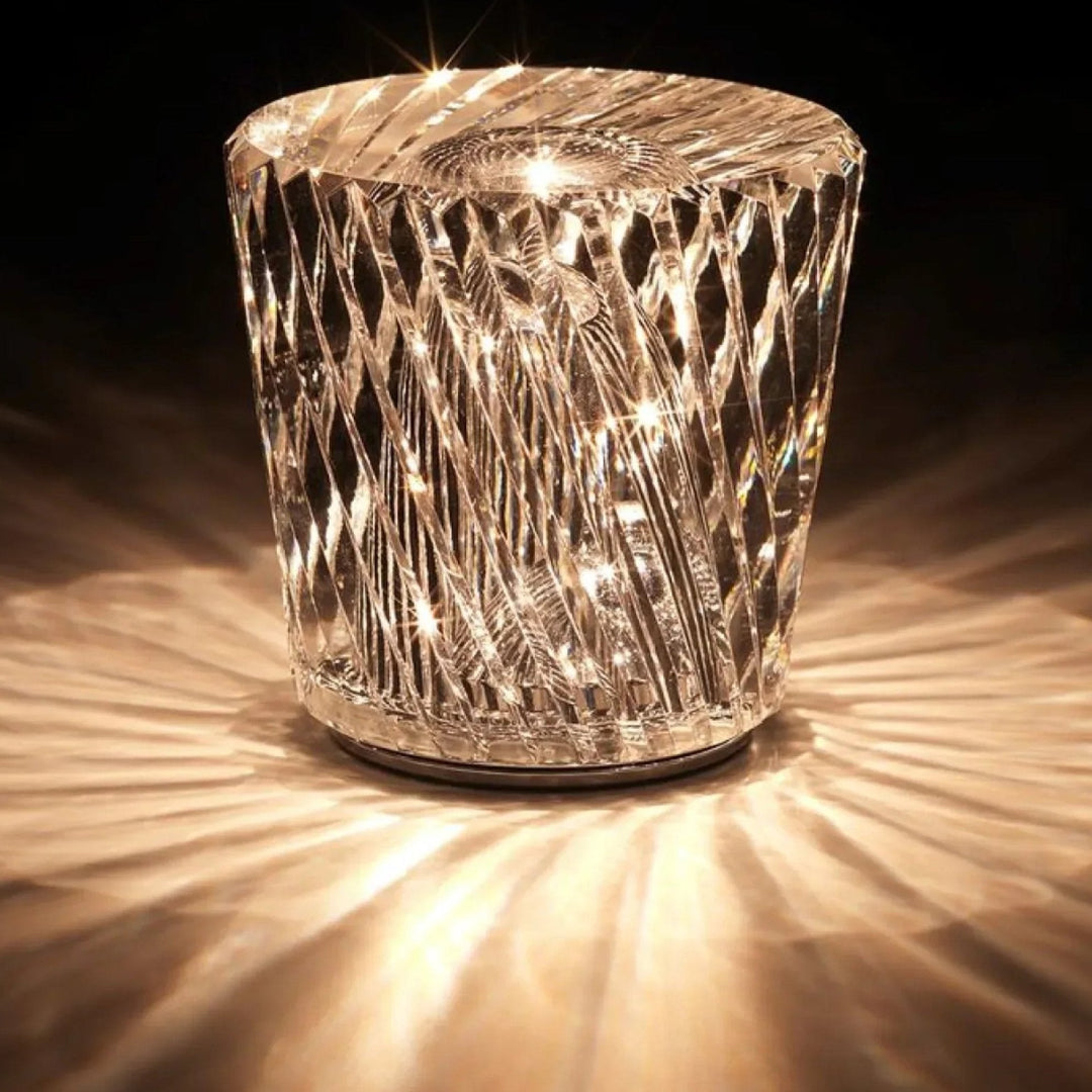 Lampe en cristal à facettes en losanges allumée sur fond sombre, projetant des rayons de lumière dorée tout autour. 13