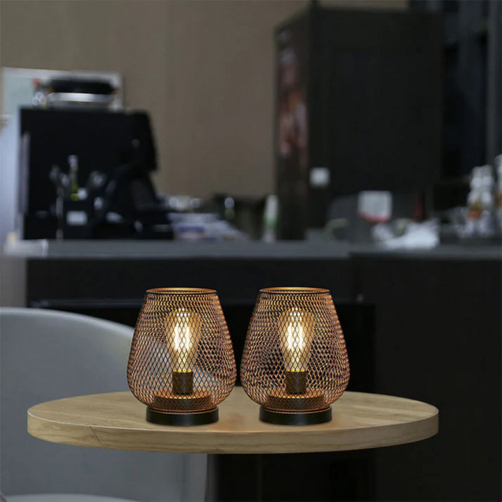 Deux lanternes allumées posées sur une petite table ronde en bois, dans un décor de café ou de bar moderne. 3