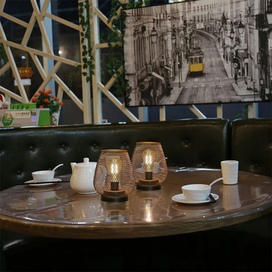 Deux lanternes allumées au centre d'une table de restaurant avec théière et tasses blanches, devant une banquette en cuir. 4