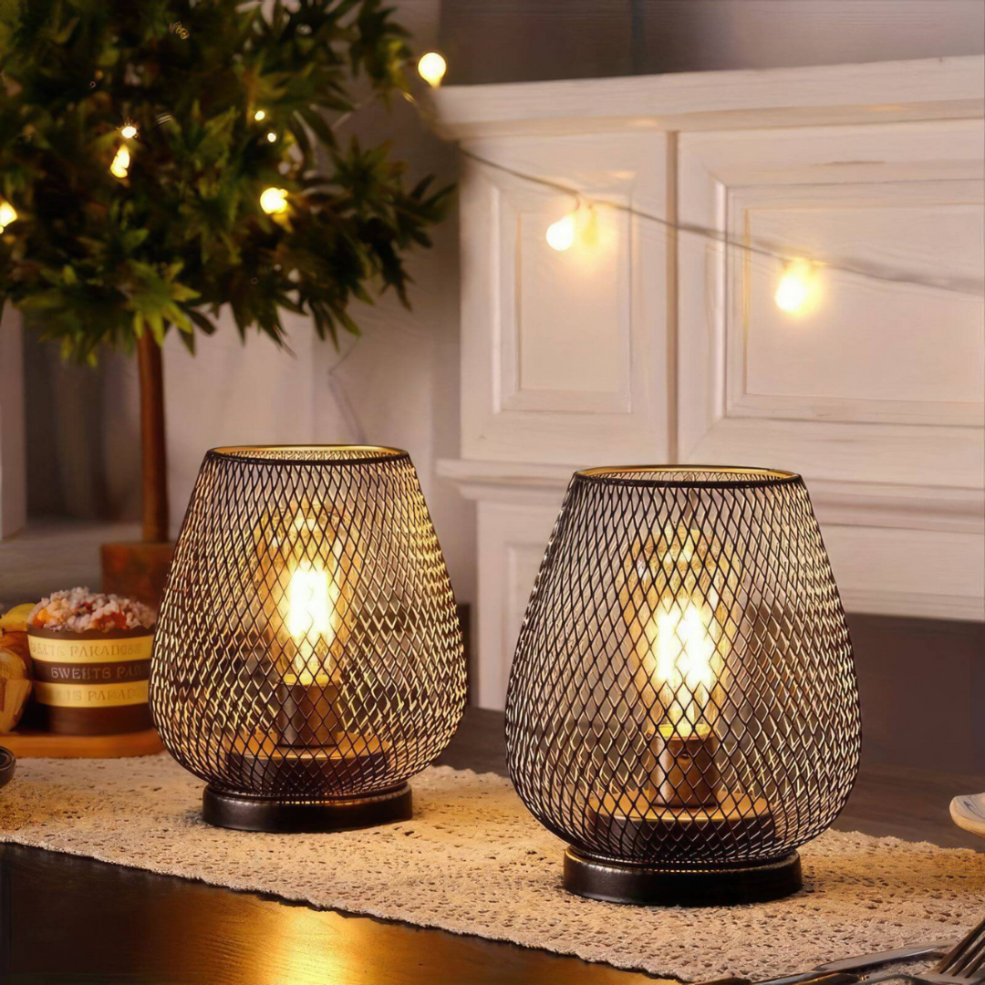 Deux lanternes allumées sur un chemin de table en dentelle, entre une guirlande lumineuse et un sapin décoré en arrière-plan. 6