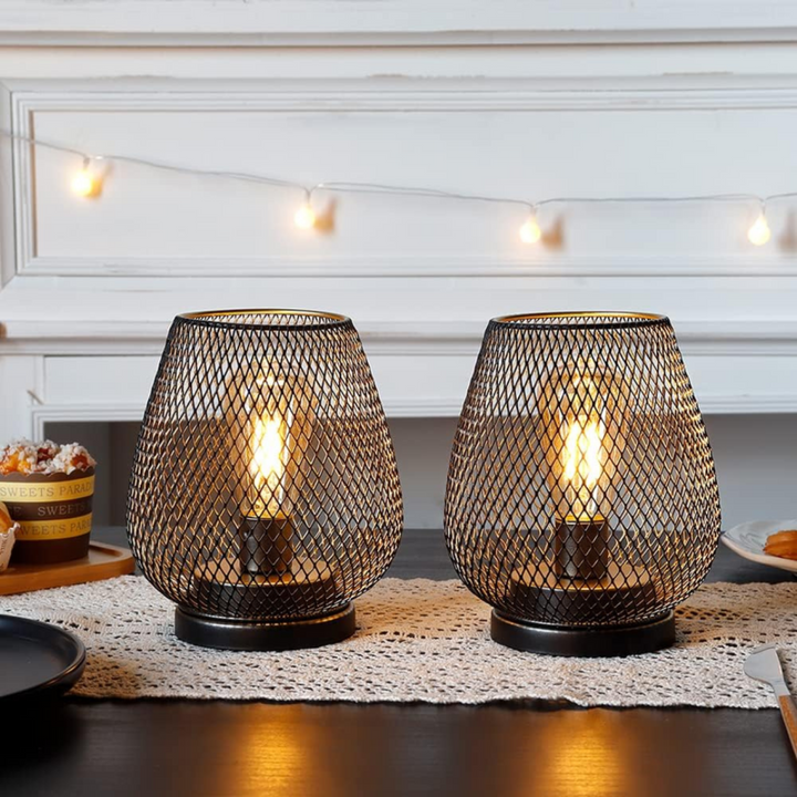 Deux lanternes à structure grillagée noire allumées sur un chemin de table en dentelle, avec une guirlande lumineuse en fond. 5