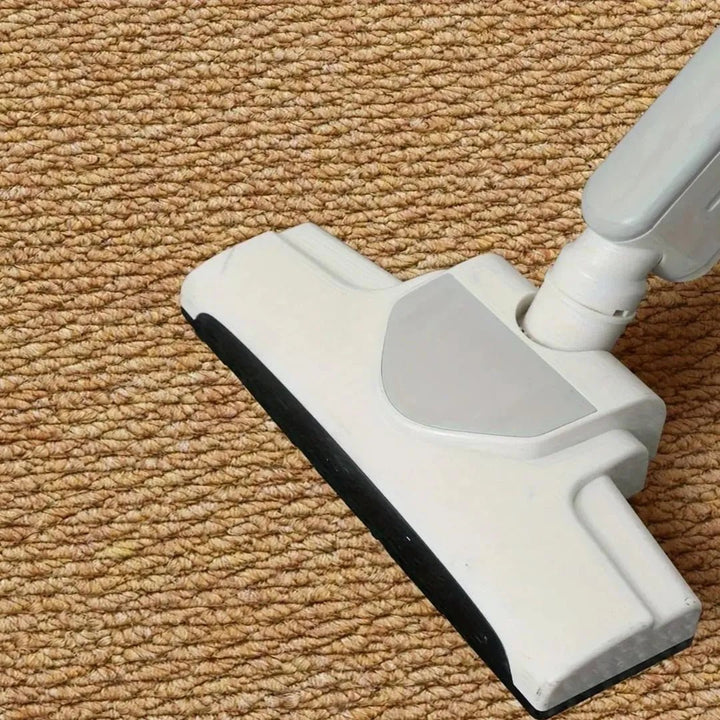 Aspirateur blanc passant sur la surface bouclée d'un tapis couleur caramel, vue rapprochée 8