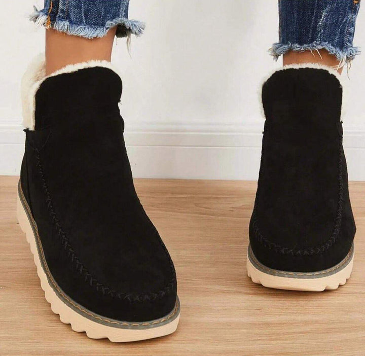 Bottines noires vues de face, portées avec un jean effiloché, avec doublure moelleuse au col et semelle épaisse crantée. 4