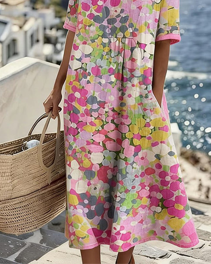 Détail du bas de la robe florale rose, jupe fluide et évasée, main dans la poche, panier en paille 4