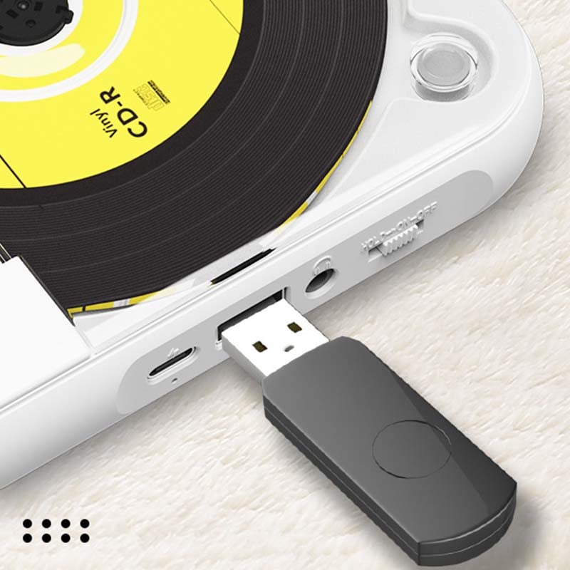 Gros plan sur le côté du lecteur blanc avec une clé USB noire branchée, à côté de la prise casque et du port de charge. 9