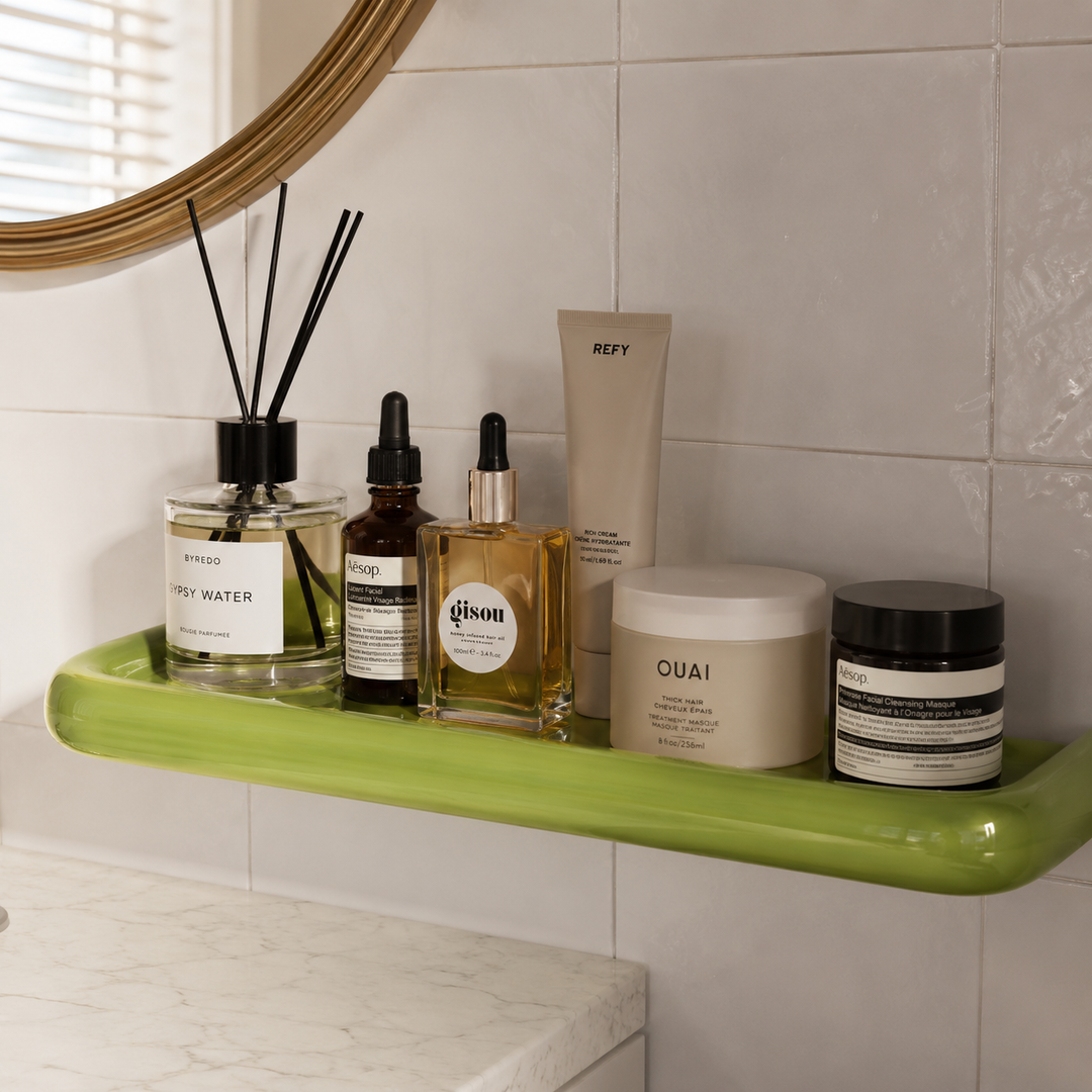 Gros plan d'une étagère verte brillante sous un miroir doré, portant diffuseur, huiles et crèmes 4