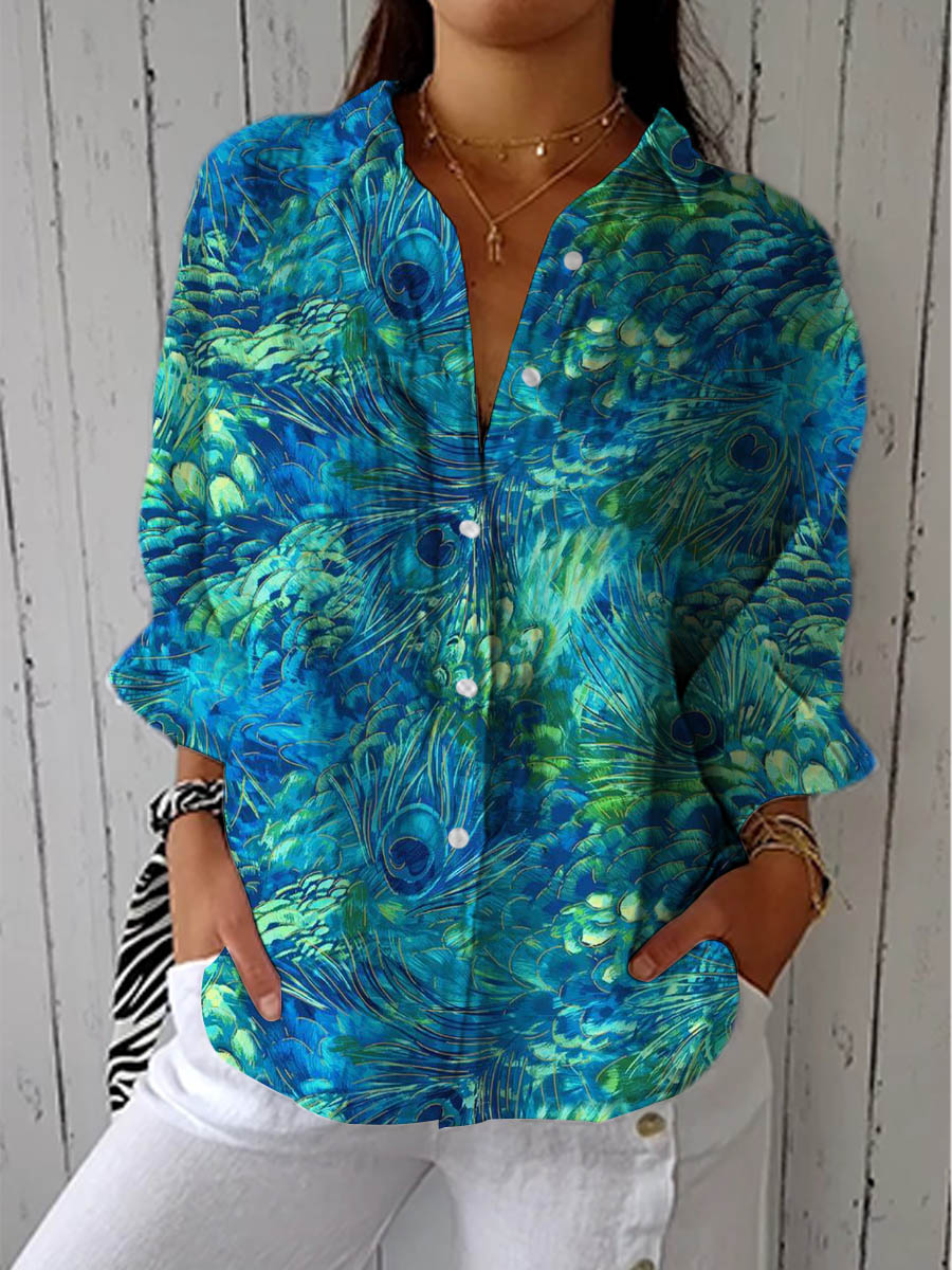 Blouse boutonnée à manches longues et motif de plumes de paon bleu et vert, portée par un mannequin avec un pantalon blanc. 1
