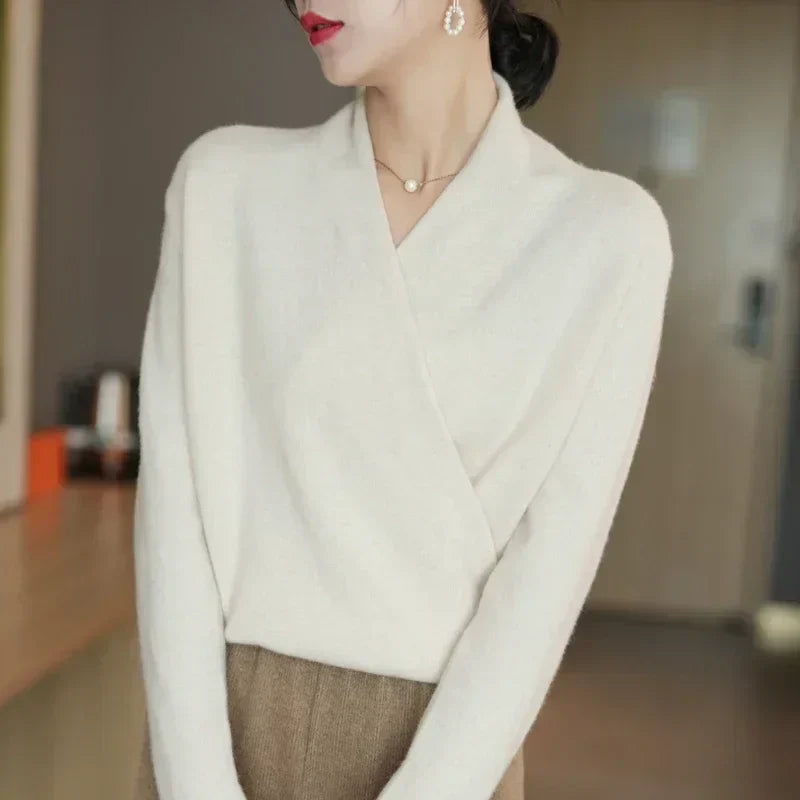 Pull croisé écru porté de trois quarts, tête tournée, jupe marron et boucles d'oreilles perlées 16