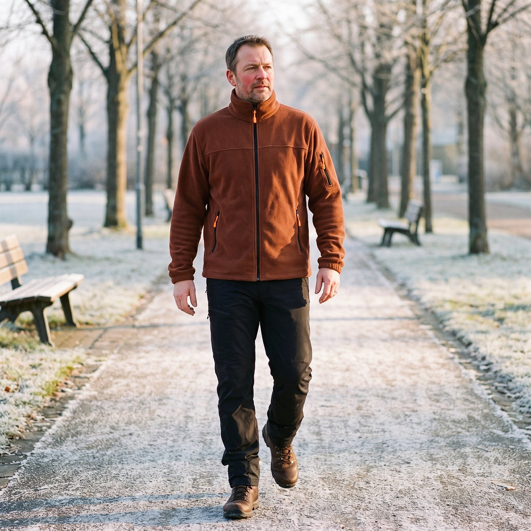 Homme portant la veste polaire marron zippée avec pantalon noir et chaussures de marche, dans un parc givré 2