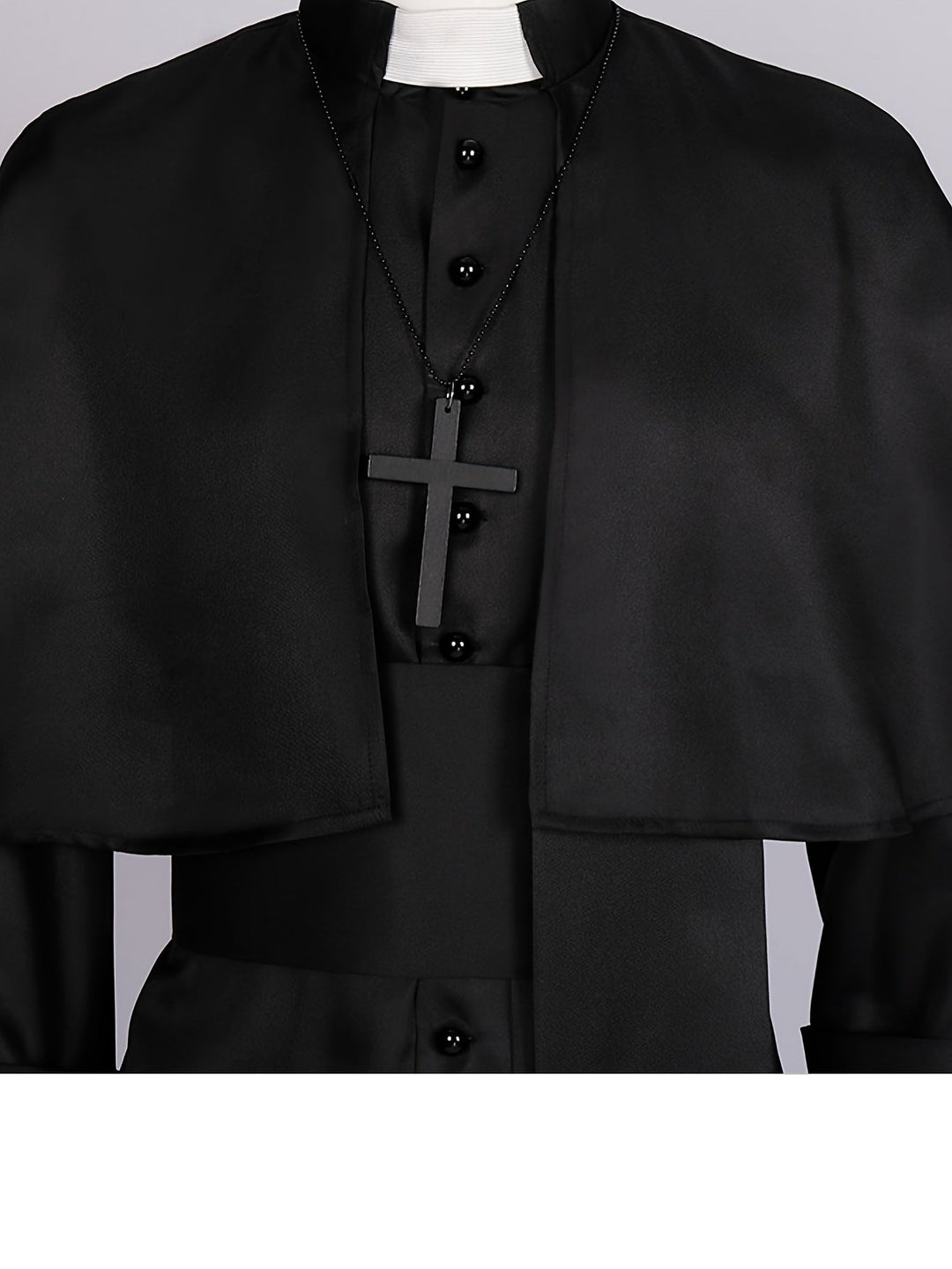 Gros plan sur le haut du costume : col blanc, croix noire sur chaîne, boutons et cape 7