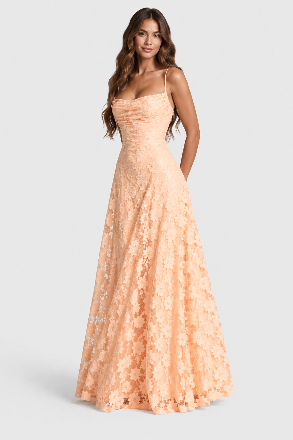 Robe pêche en dentelle à grandes fleurs, encolure drapée et jupe longue évasée, portée de face, mains dans les poches. 16