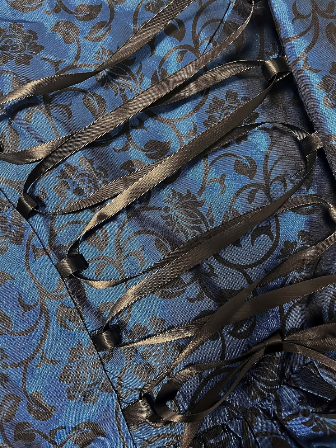 Gros plan sur le laçage en ruban noir satiné sur le tissu bleu à motifs floraux noirs. 5