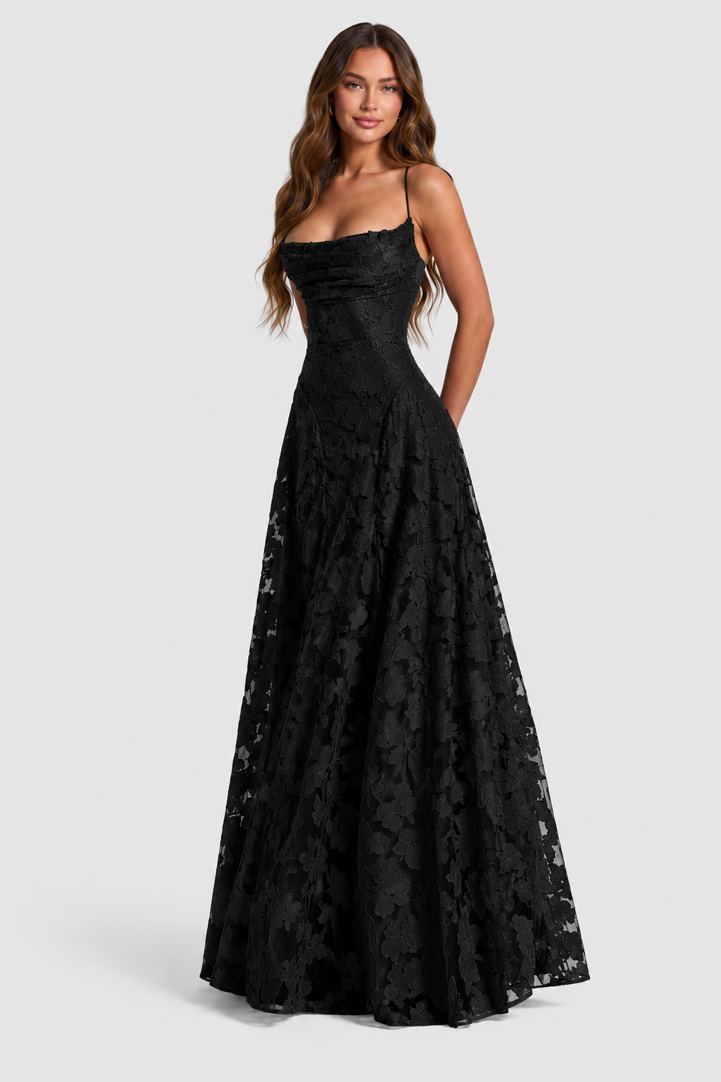 Robe noire en dentelle florale, encolure drapée et fines bretelles, longue jupe évasée, portée de face par une mannequin souriante. 10