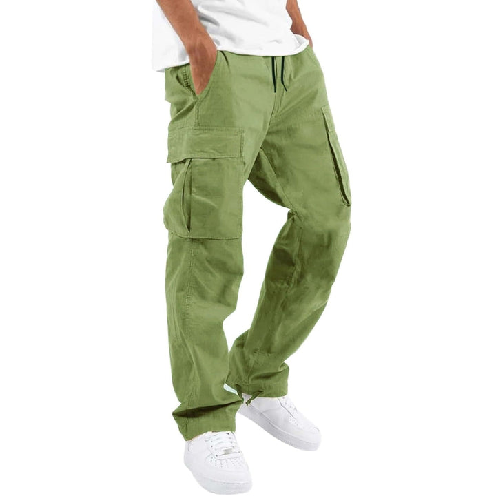 Pantalon cargo vert clair porté par un modèle avec t-shirt blanc et baskets blanches, mains dans les poches. 9