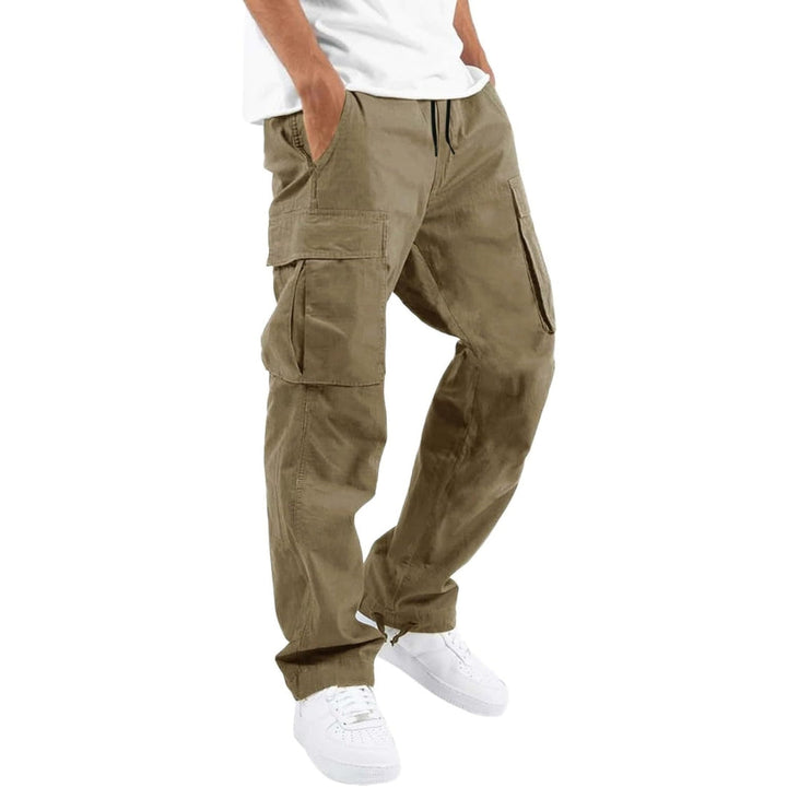 Pantalon cargo beige porté par un modèle avec t-shirt blanc et baskets blanches, mains dans les poches, vue de trois quarts. 3