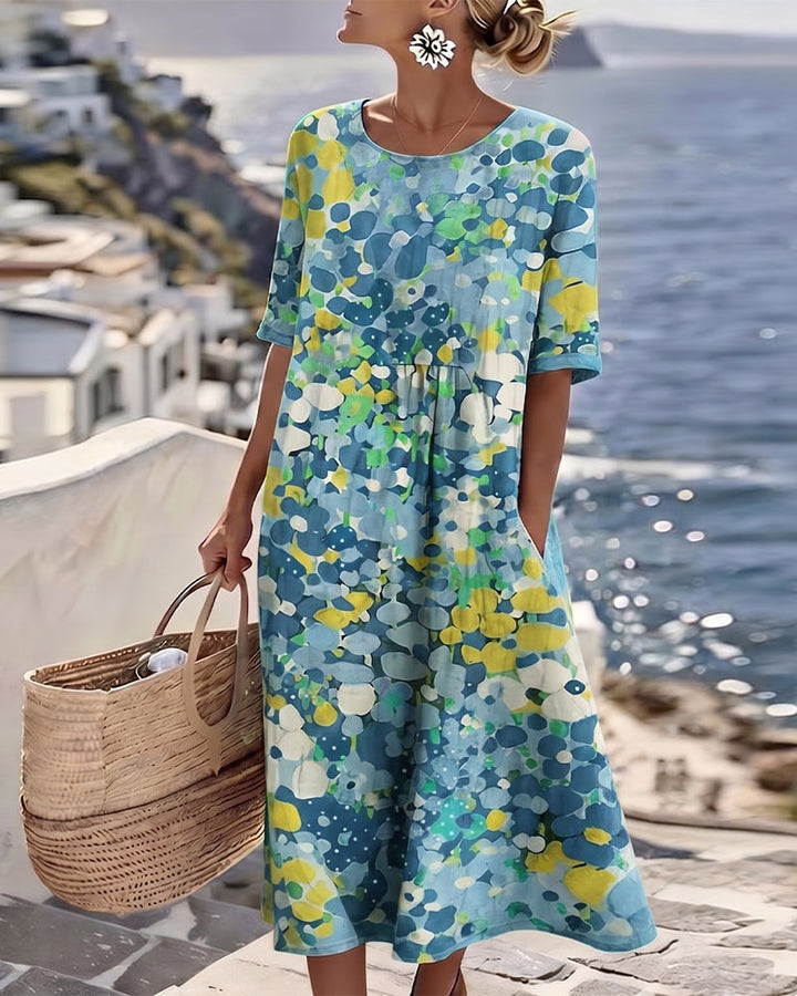 Robe à motif floral bleu, jaune et vert portée en pied, coupe fluide, panier de paille à la main 9