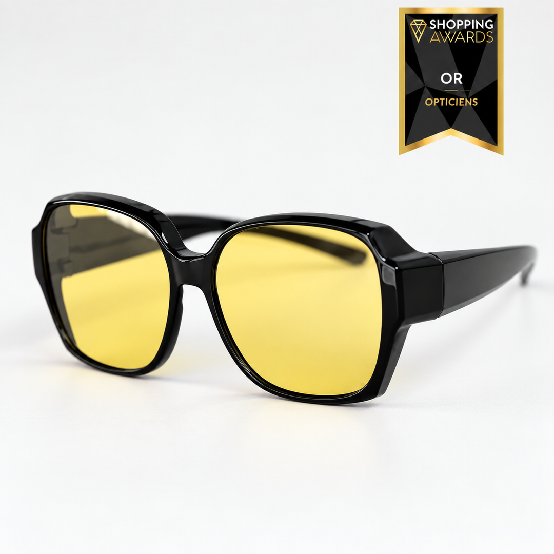 Lunettes surdimensionnées à monture noire brillante et verres jaunes, vues de trois quarts sur fond blanc, modèle à enfiler sur les lunettes de vue. 1