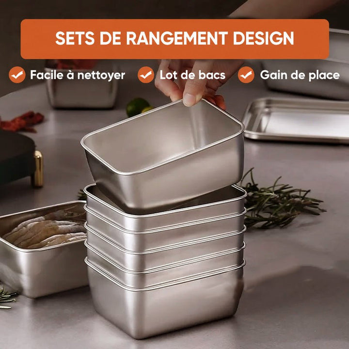 Main posant un contenant en inox sur une pile de boîtes empilées, illustrant le rangement compact de l'ensemble sur un plan de travail. 4