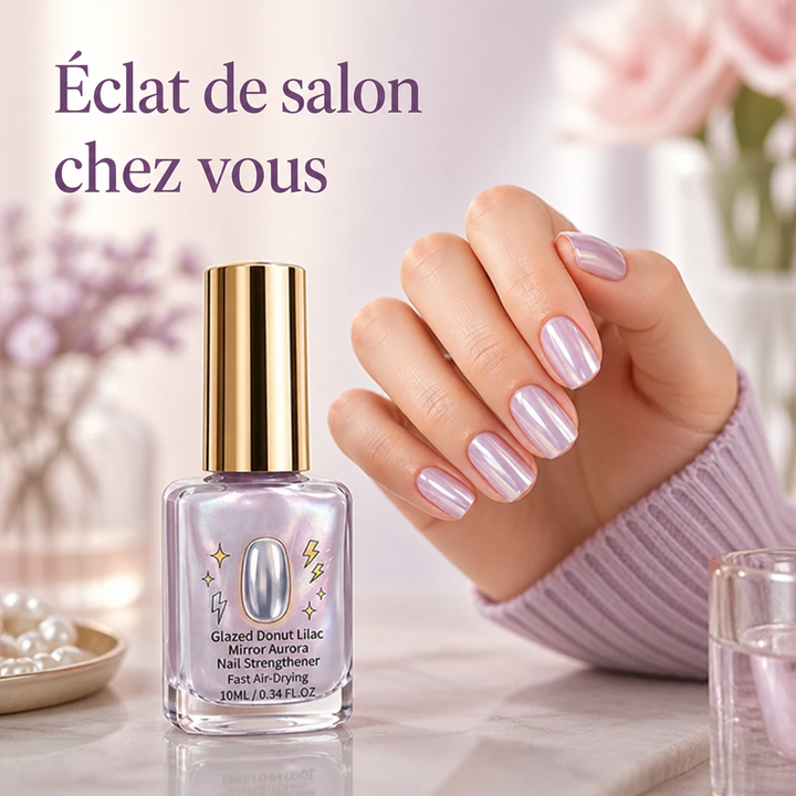 Flacon à bouchon doré posé sur du marbre, près d'une main aux ongles lilas irisés 1
