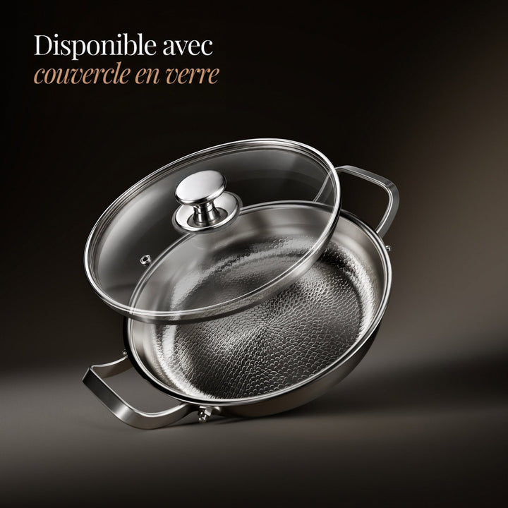 Poêle inclinée avec son couvercle en verre transparent posé au-dessus, bouton en métal brillant, sur fond sombre. 3