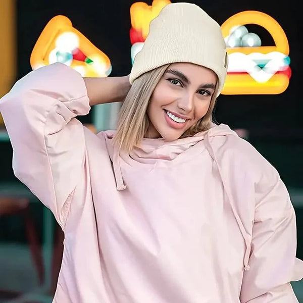 Jeune femme souriante portant le bonnet beige clair avec un sweat rose à capuche 2
