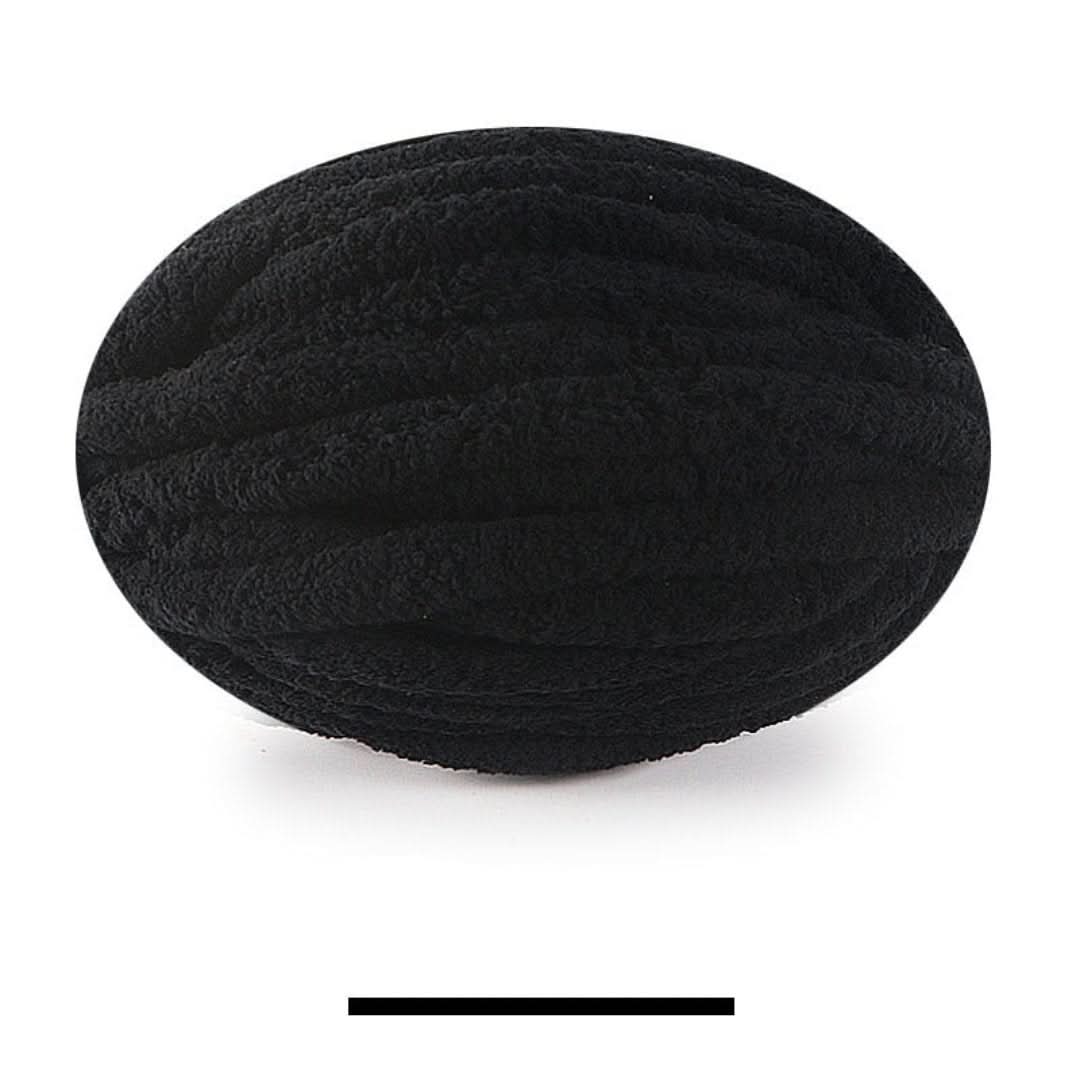 Pelote ovale de fil épais et moelleux noir, sur fond blanc, avec un échantillon de la teinte en dessous. 20