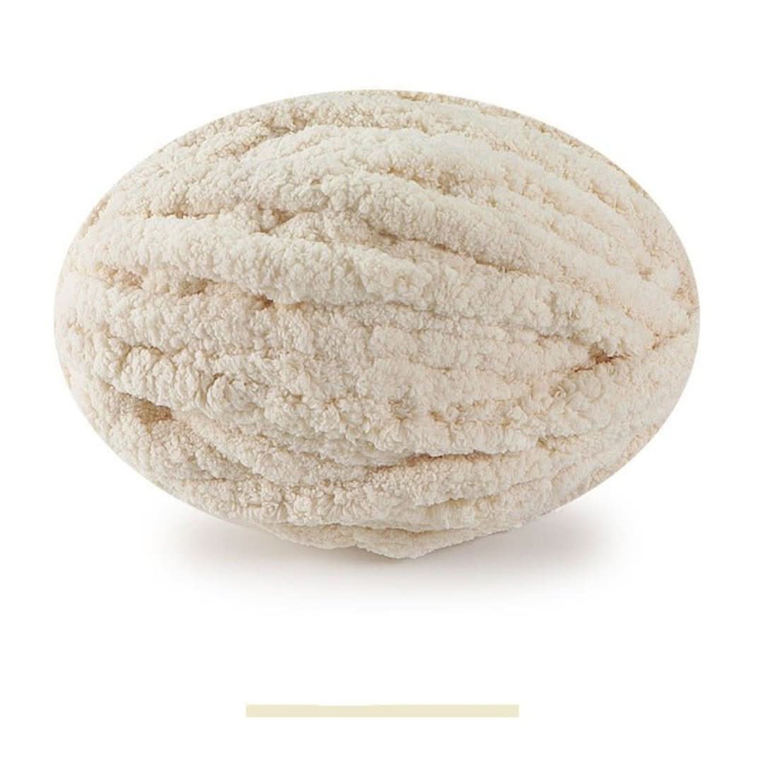 Pelote ovale de fil épais et moelleux beige clair, sur fond blanc, avec un échantillon de la teinte en dessous. 9