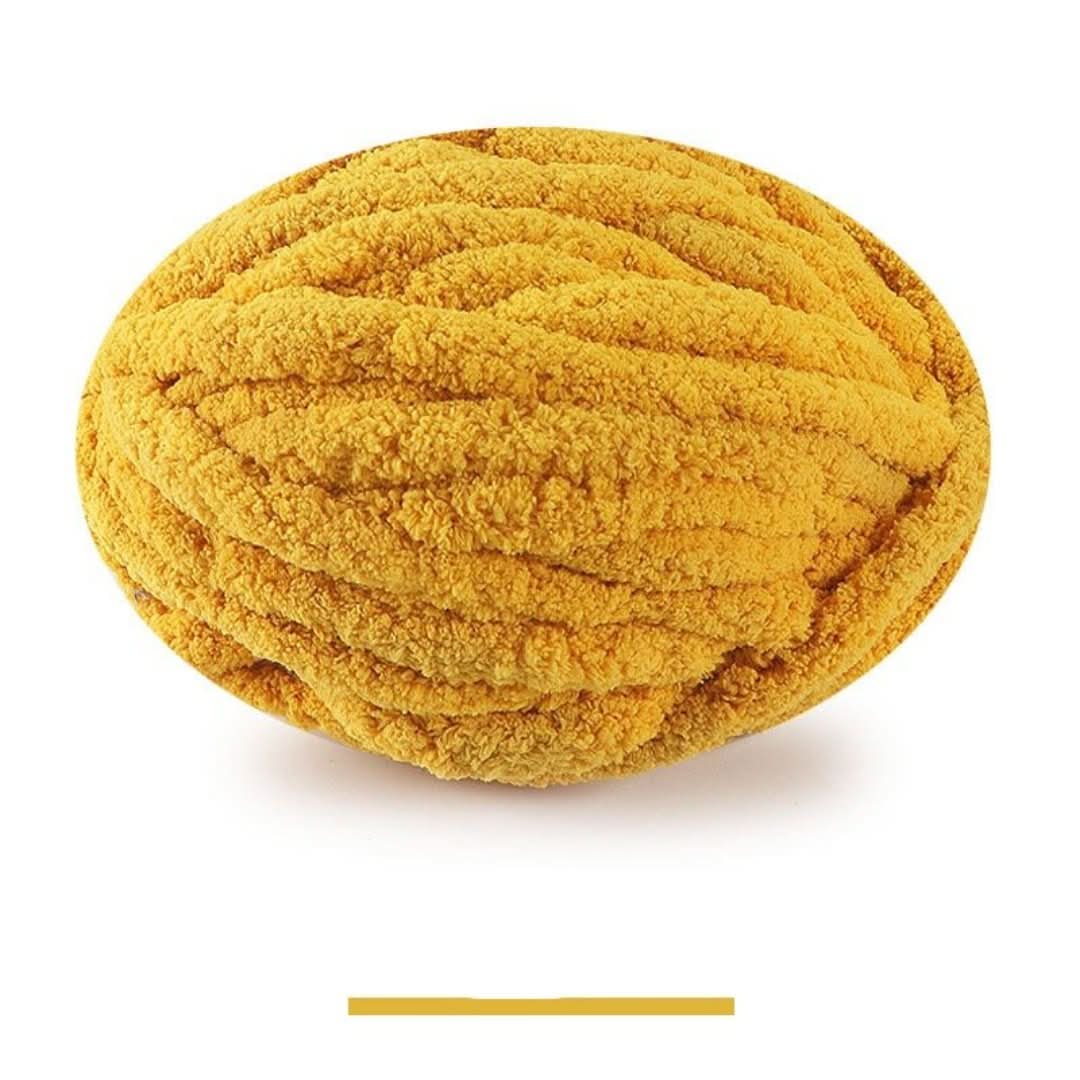 Pelote ovale de fil épais et moelleux jaune moutarde, sur fond blanc, avec un échantillon de la teinte en dessous. 12