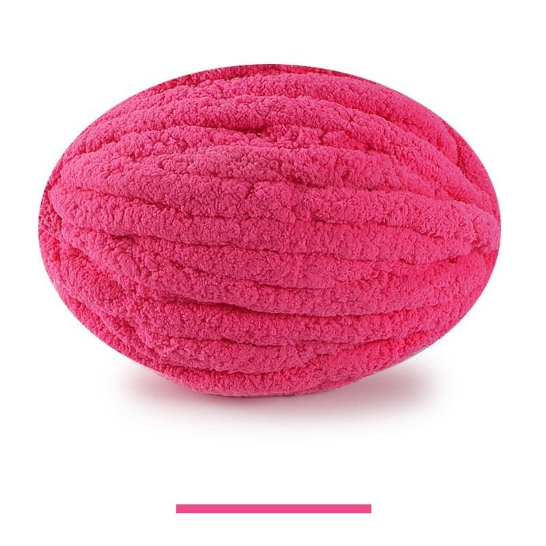 Pelote ovale de fil épais et moelleux rose fuchsia vif, sur fond blanc, avec un échantillon de la teinte en dessous. 15