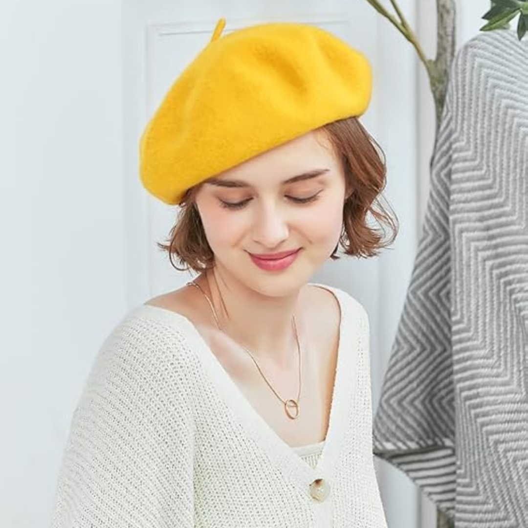 Femme souriante portant un béret jaune avec un gilet blanc, collier doré, regard baissé 16