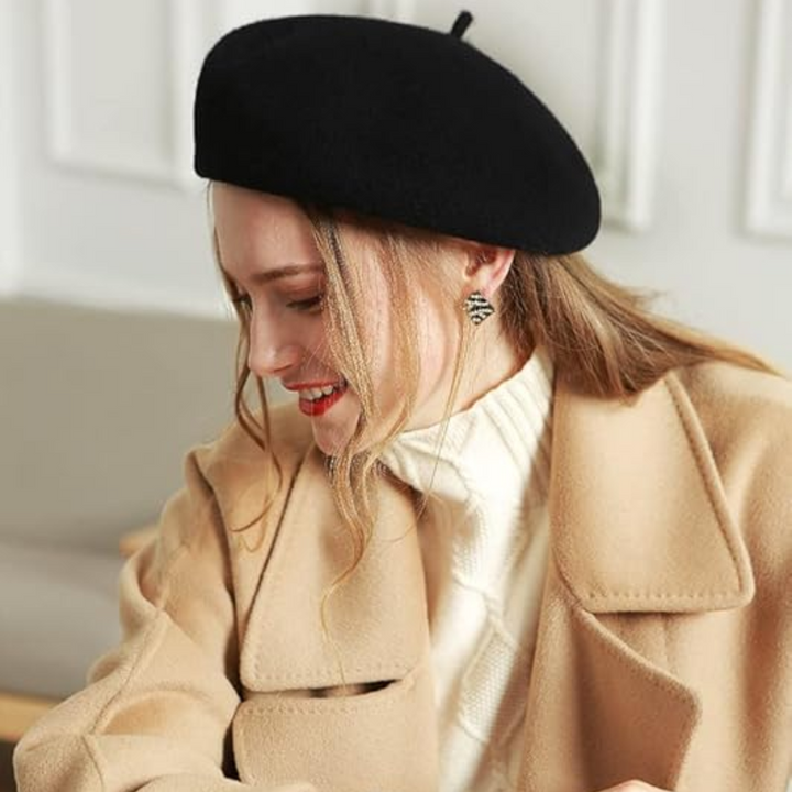 Béret noir en laine porté par une femme souriante en manteau camel, vue de profil 22