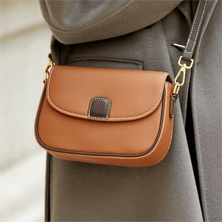 Sac marron caramel porté en bandoulière sur un manteau gris, avec liseré brun foncé et mousquetons dorés 2