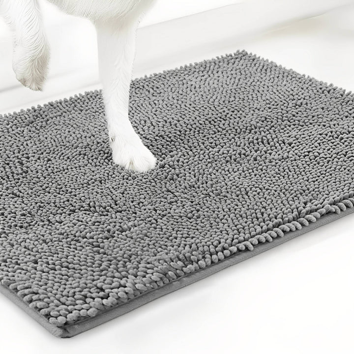 Patte blanche de chien posée sur le tapis en chenille gris clair, vue d'angle sur fond blanc. 12